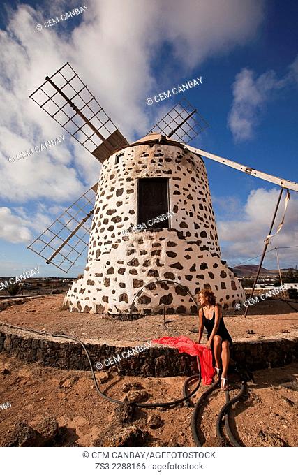 Woman posing in front of the windmill near Tefia, La Oliva, Fuerteventura, Canary Islands, Spain, Europe