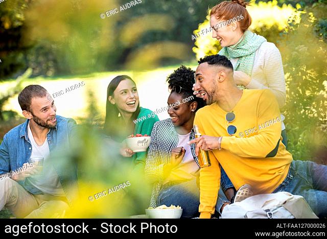 Happy young friends having picnic in public park