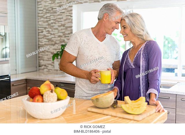 Caucasian couple touching foreheads in kitchen