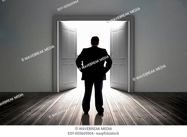 Businessman looking at door showing bright light