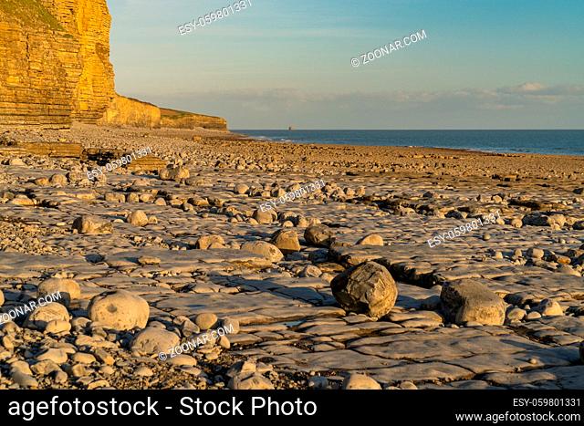 The stones and cliffs of Llantwit Major Beach in the evening sun, South Glamorgan, Wales, UK - with the Bristol Channel in the background