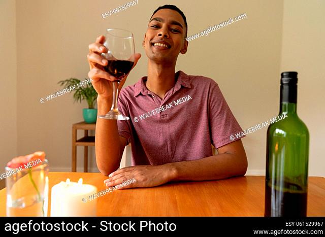 Portrait of mixed race man holding glass of red wine looking at camera smiling