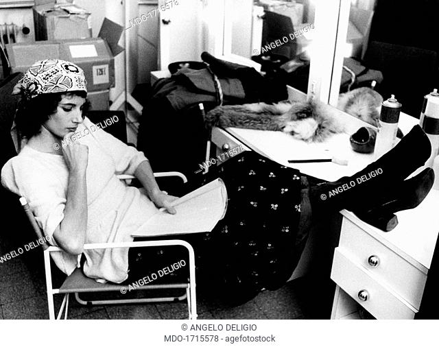 Paola Pitagora is studying a script while seated with her legs leaning on a desk . The Italian film, theatre and television actress Paola Pitagora (born Paola...