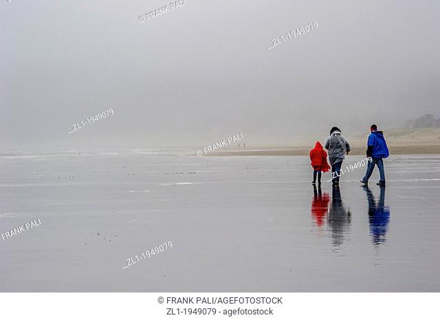 Family walking on rainy day on Cannon Beach.Cannon Beach, Oregon USA