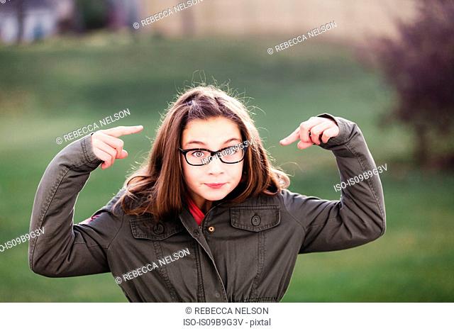 Portrait of girl in spectacles pointing at her face