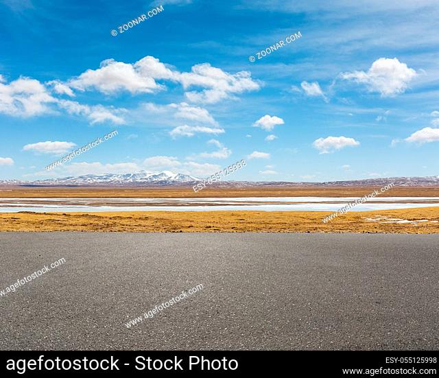 empty asphalt road and snow area plateau against a blue sky