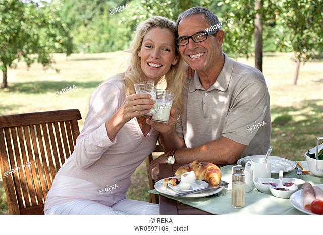 Smiling mature couple outdoors at breakfast table