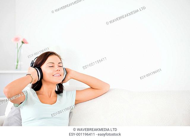 Delighted brunette listening to music in her living room