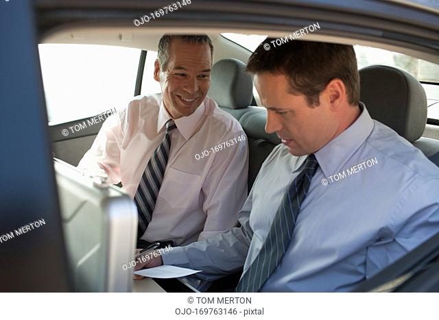 Businessmen working in backseat of car