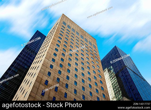 New York City, USA - June 21, 2018: Low angle view of the buildings of The United States Mission to the United Nations in Manhattan, view against moving clouds