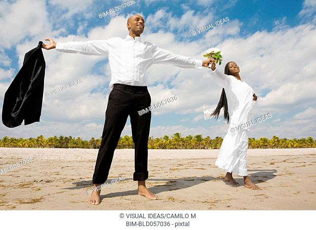 African bride and groom with arms outstretched