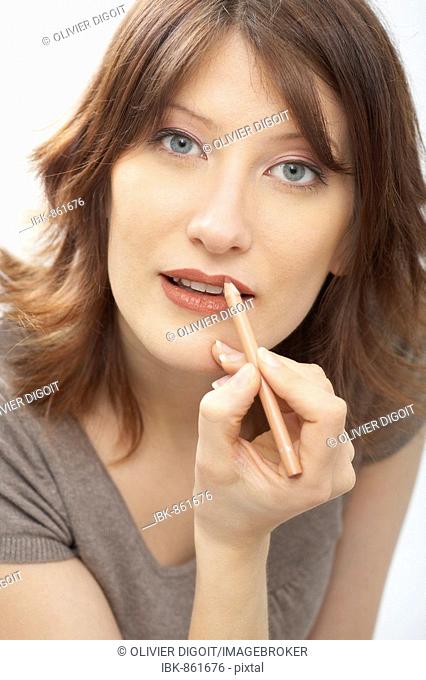 Portrait of a woman applying lipliner