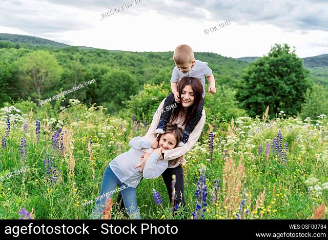 Mother with daughter and son in lupine flowers meadow