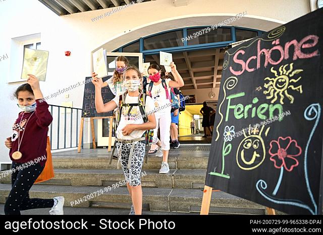 29 July 2020, Baden-Wuerttemberg, Friedrichshafen-Fischbach: Pupils of the Fischbach primary school on Lake Constance hold up their reports while leaving the...