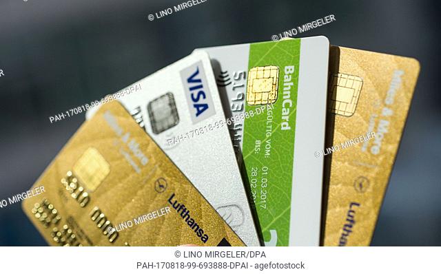 ILLUSTRATION - Credit cards by different private companies being held by a hand in Berlin, Germany, 18 August 2017. From right to left: Lufthansa, Air Berlin