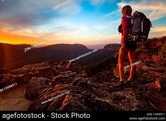 Female hiker on bushwalk in upper Blue Mountains, watching a sunset from the peak
