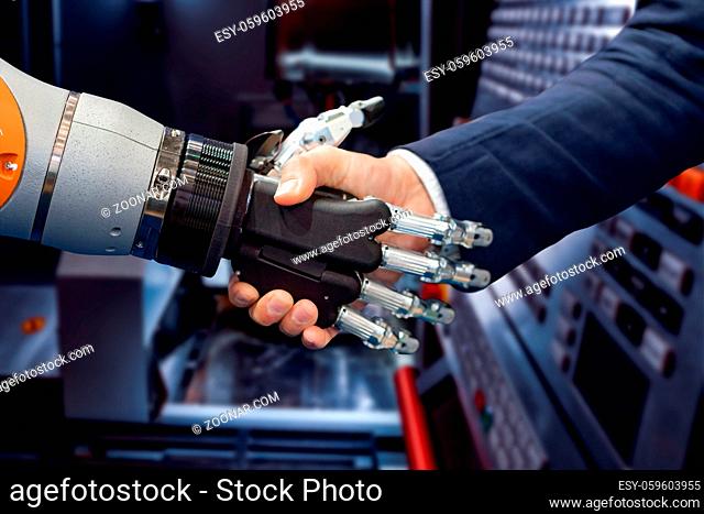 Hand of a businessman shaking hands with a Android robot. The concept of human interaction with artificial intelligence