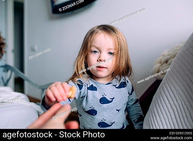 little girl in the bedroom takes something out of the hand