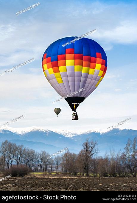 Multicolored Balloon in the blue cloudy sky. Mountain background