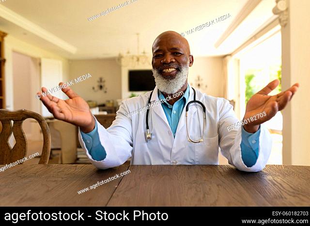 Portrait of smiling senior african american male doctor in lab coat during video consultation