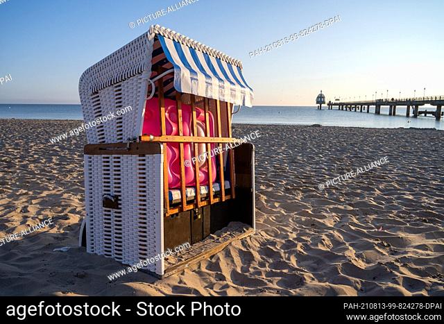 12 August 2021, Mecklenburg-Western Pomerania, Zinnowitz: Locked behind the wooden grating of a beach chair lies an air mattress