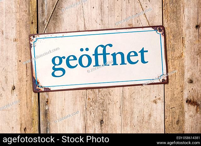 Old metal sign in front of a rustic wooden wall - Open - geoeffnet German