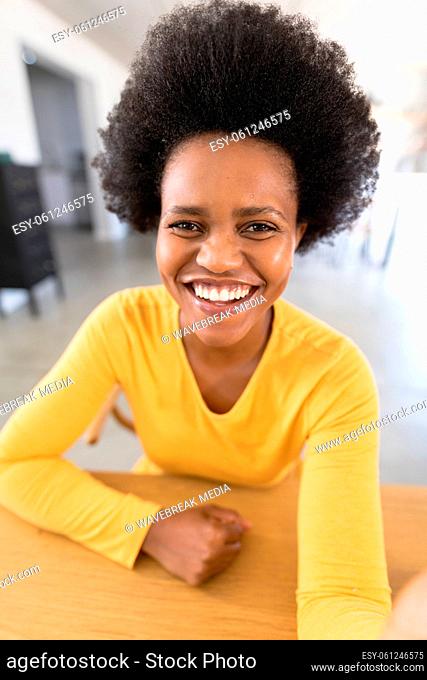 Portrait of happy african american mid adult female freelancer with afro hairstyle at home office