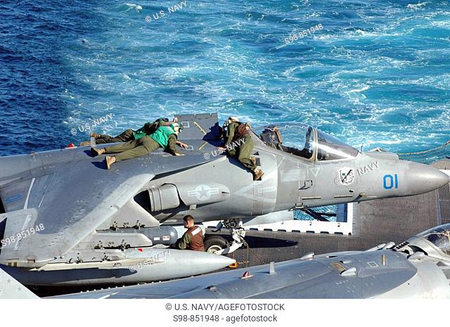 Pacific Ocean- Marines aboard amphibious assault ship USS Peleliu (LHA 5) conduct maintenance on an AV-8B Harrier assigned to the 'Blacksheep' of Marine Attack...