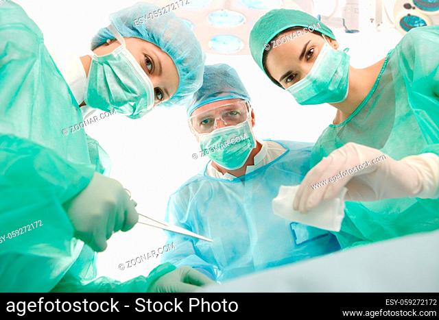 Portrait of surgeons at work, operating in uniform, looking at camera