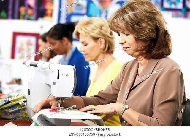 Group Of Women Using Electric Sewing Machines In class