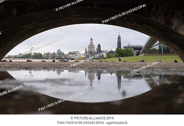 16 May 2019, Saxony, Dresden: The backdrop of Dresden's old town is reflected in a puddle below the Marienbrücke bridge. Photo: Sebastian...