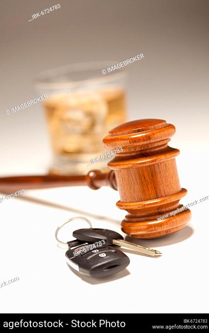 Gavel, alcoholic drink & car keys on a gradating to white background, drinking and driving concept