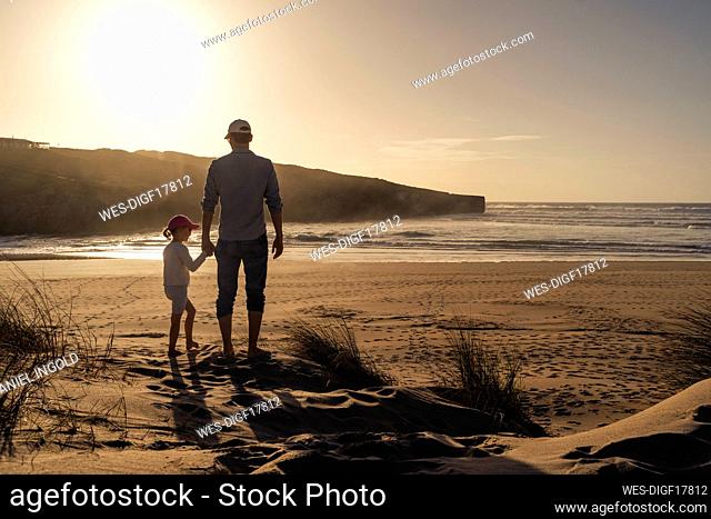 Father and daughter enjoying sunset at beach