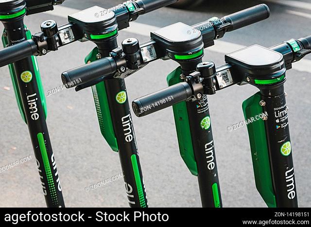Berlin, Germany - June, 2019: Row of parked electric E scooters , escooter or e-scooter of the company LIME on sidewalk in Berlin