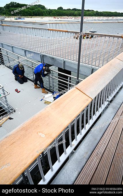 22 June 2021, Mecklenburg-Western Pomerania, Koserow: Workers install a railing on the new pier in the Baltic resort of Koserow on the island of Usedom
