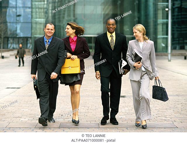 Group of business people walking together outside, full length, front view