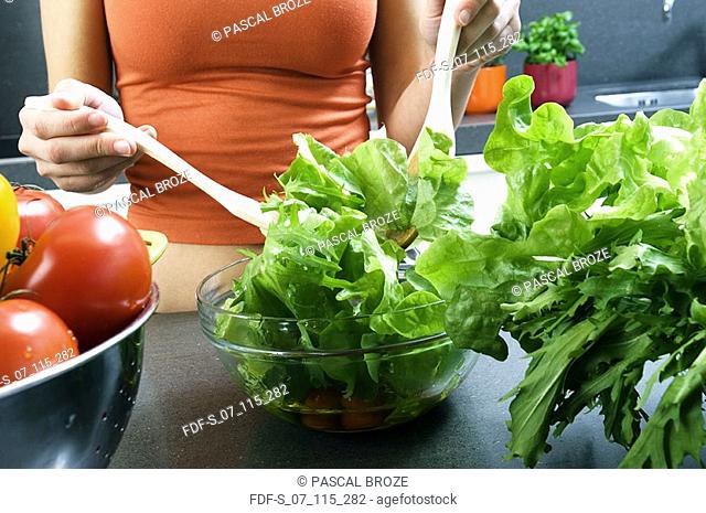Mid section view of a woman preparing salad