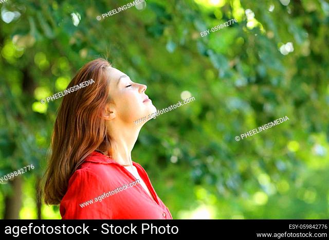 Profile of a woman in red breathing fresh air in a green park