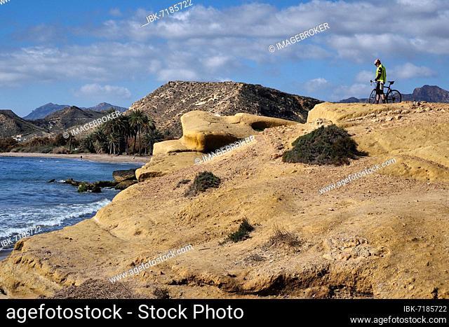 Biker at rocky bay near Cocedores, biker on rocks by the sea, Aguilas, Murcia, Spain, Europe