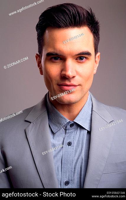 Studio shot of young handsome businessman against gray background
