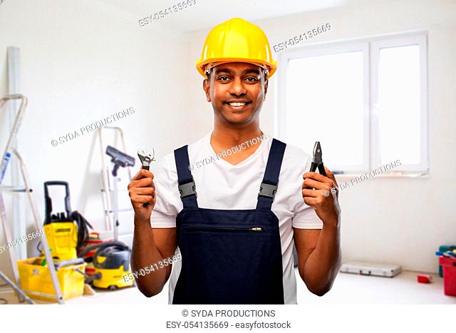 indian builder in helmet with wrench and pliers
