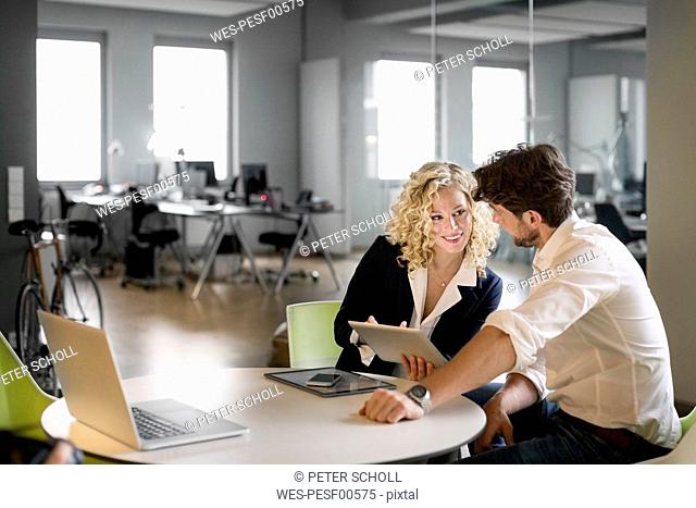 Businessman and woman discussing project in office, using digital tablet