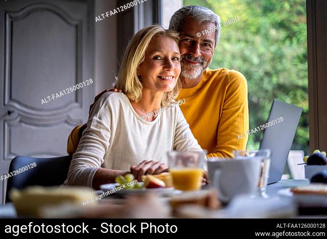 Portrait of smiling mature couple using laptop at home