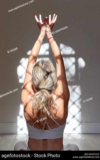 Mature woman with hands cupped exercising at home