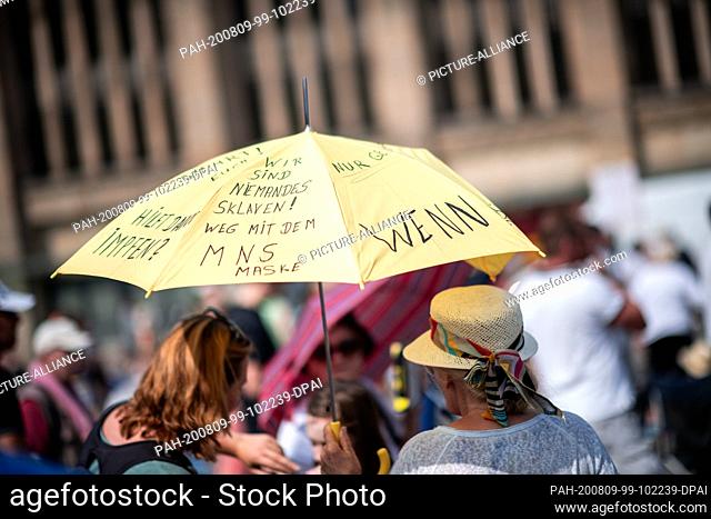 09 August 2020, North Rhine-Westphalia, Dortmund: Participants of the demonstration hold an umbrella with ""We are nobody's slaves! Away with the MNS masks""...