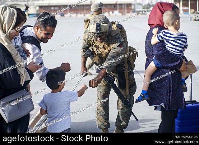 A United States Marine assigned to 24th Marine Expeditionary Unit fists bumps a child evacuee during a military drawdown at Hamid Karzai International Airport