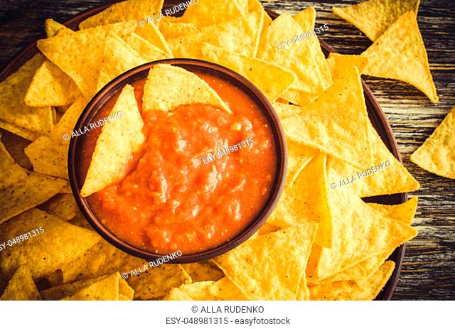 Nachos corn chips with spicy tomato sauce. Mexican food concept. Yellow corn totopos chips with salsa sauce. Top view