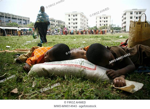 Children sleeping in the shade of trees while their parents trying to buy rice at a fair price shop, run by Bangladesh Rifles, BDR, in Dhaka Bangladesh April 04