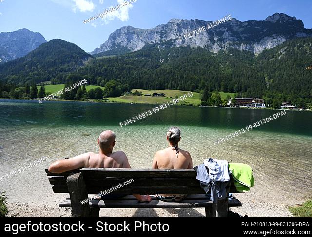 13 August 2021, Bavaria, Hintersee: A couple enjoys the cool Hintersee with their feet in the water. The mountain lake lies at over 789 above sea level