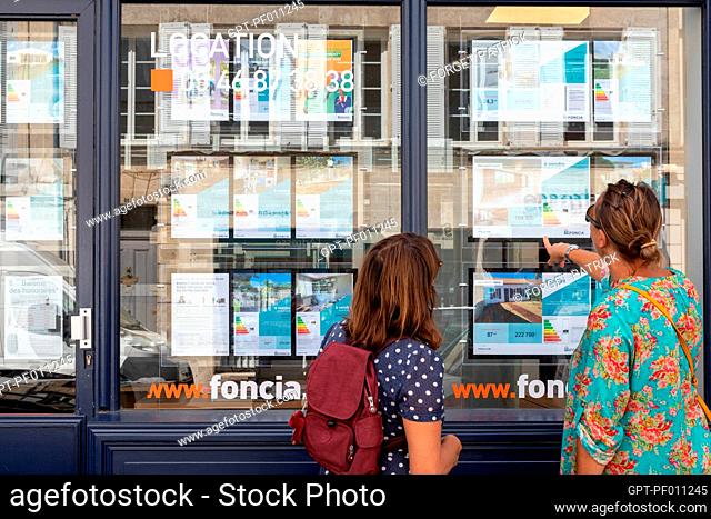 PASSERS-BY IN FRONT OF THE STOREFRONT WITH REAL ESTATE ADS, REAL ESTATE AGENCY FOR RENTALS, SALES AND MANAGEMENT, ROCHEFORT, CHARENTE-MARITIME, FRANCE